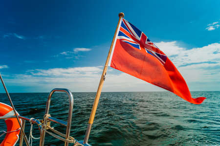 The uk red ensign the british maritime flag flown from yacht sail boat, blue sky and baltic sea. Summer and travel voyageの写真素材