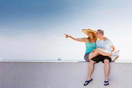 Relationship goals, love and friendship concept. Man and woman sitting together outside hugging, having date. She is pointing at somethingの写真素材