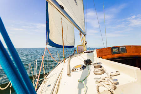 Yachting on sail boat during sunny summer weather on calm blue sea water. Sporty transportation...
