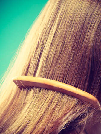 Haircare concept. Straight brown hair with wooden comb closeupの写真素材