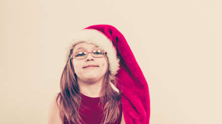 Christmas holiday concept. Toddler girl wearing Santa Claus hat and christmassy dress.の写真素材
