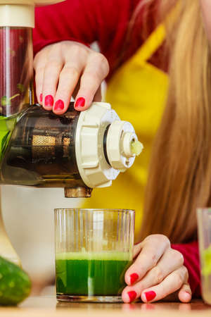 Drinks good for health, diet breakfast concept. Woman in kitchen making green healthy vegetable smoothie juice from green vegetablesの写真素材