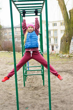 Sport and recreation. Fit slim sporty teen girl stretching warming up outdoor on fitness equipments....
