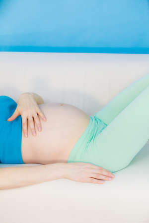 Pregnant woman future mother lying on couch relaxing, touching tender her naked belly. Pregnancy,...