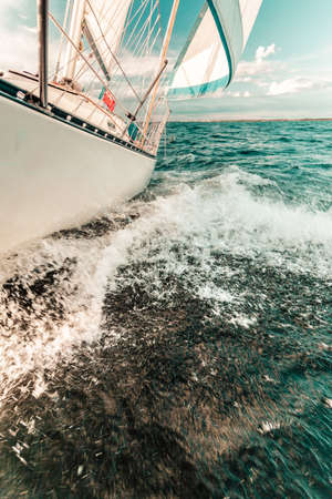 Yachting on sail boat bow stern shot splashing sea water. Sporty transportation conept.の写真素材