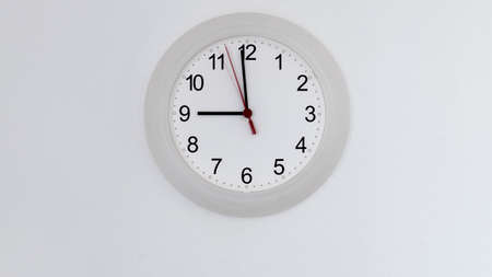 Clock hanging on white wall showing nine hours.