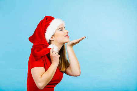 Xmas, seasonal clothing, winter christmas concept. Happy young woman wearing Santa Claus helper costume sending air kissesの写真素材