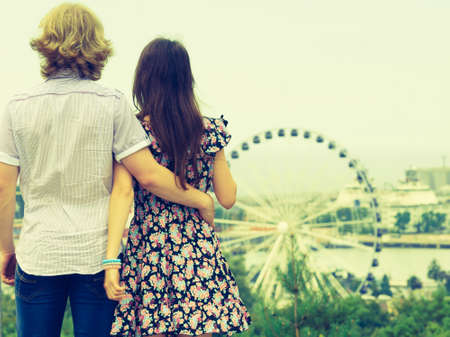 Man and woman having romantic date looking at city panorama view and ferris wheel outdoor. Couple romance moments concept.の写真素材
