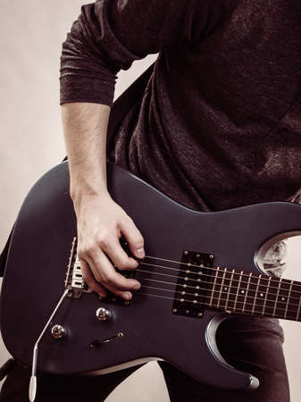 Male hands with electric guitar. Close up, part body adult person is holding instrument and playing. Hobby, music conceptの写真素材