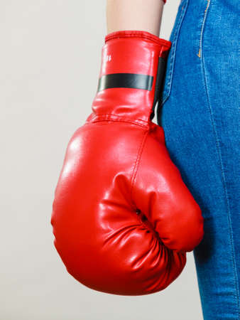 Unrecognizable woman wearing red boxing glove, and tight blue jeans. Grey background.の写真素材