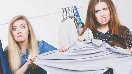 Two funny women arguing with each other during shopping about piece of clothing. Sales madnessの写真素材