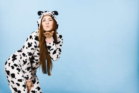Happy teenage girl in funny nightclothes, pajamas cartoon style sending kiss, positive face expression, studio shot on blue.の写真素材