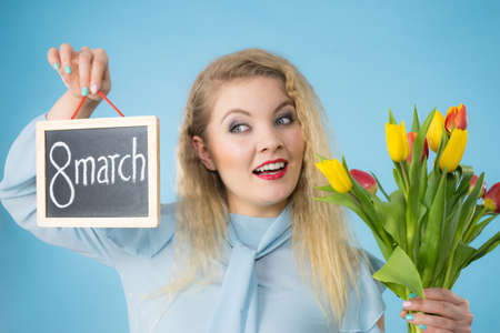 International women day. Beautiful woman blonde hair fashion make up holding red yellow tulips and...
