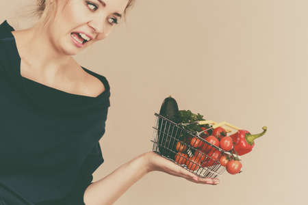Adult woman do not like to eat vegetables, healthy food, vegetarian products. Female holding small...