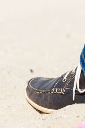 Pefect footwear for summer concept. Pair of dark sneakers on sandy beachの写真素材