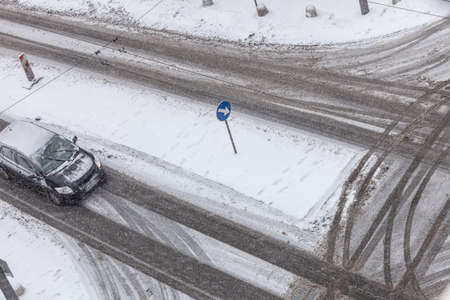 Bad weather conditions. Car on road covered with snow during winter time. High angle view from top.