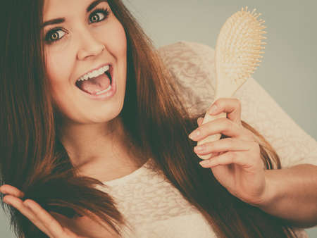 Haircare and morning hairstyling concept. Happy woman brushing her long dark brown hairの写真素材