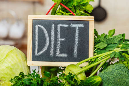 Many green vegetables in kitchen and board with diet sign. Healthy eating concept.の写真素材