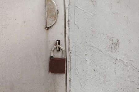 Old fashioned padlock on light grey steel door. Industrial objects and details concept.の写真素材