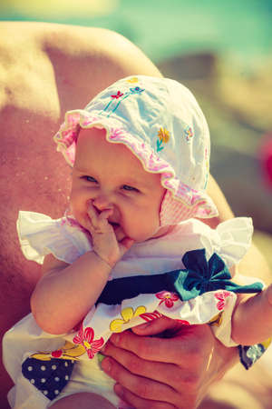 Child in hat held by man on summertimeの写真素材