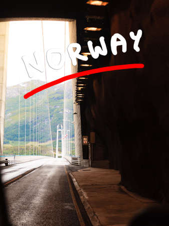 Tunnel at norwegian mountains and suspension bridge in the background. View from car. Infrastructure in Norway Scandinaviaの写真素材