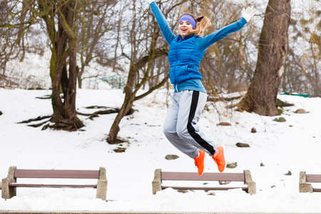 Outdoor sport exercises, sporty outfit ideas. Woman wearing warm sportswear training exercising outside during winter, jumping out of joy.の写真素材
