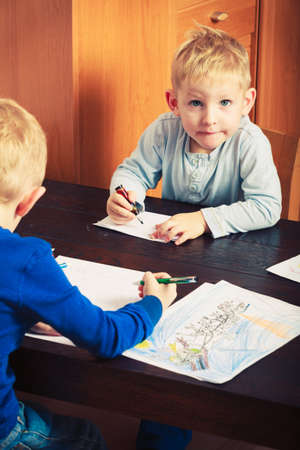 Creative hobby, kids passion concept. Two boys playing together, drawing pictures on paperの写真素材