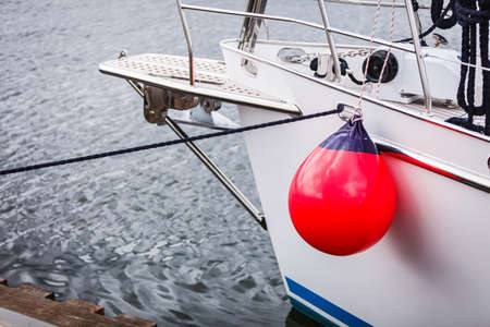 Yachting, sailing conept. Sailboat in the sea with many red fenders buoy.