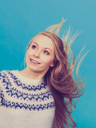 Hairstyles ideas, happiness concept. Crazy teenage woman wearing winter jumper with windblown blonde hairの写真素材