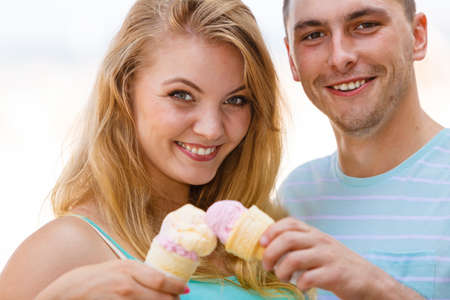 Relationship goals, summer love concept. Man and woman being on date, eating ice cream on beachの写真素材