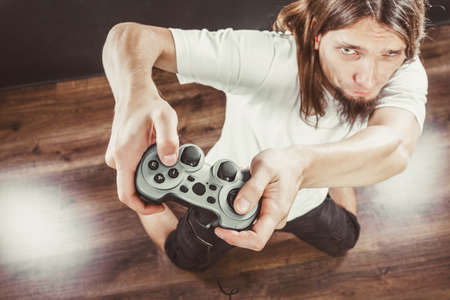Addiction. Stressed depressed young man playing gaming on pad. Angry guy with controller pad play...