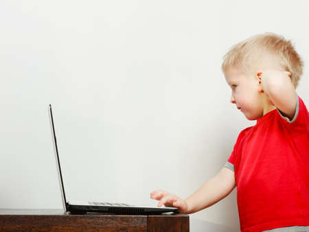 Children and technology, spending free time online concept. Little boy using laptop computer playing gamesの写真素材