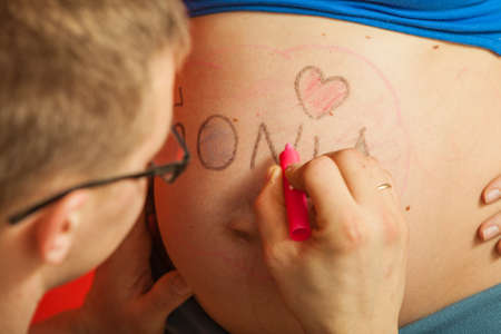 Parenthood, waiting for baby concept. Pregnant woman big belly with drawings made by fatherの写真素材