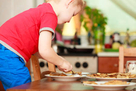 Morning routine in family, healthy diet for children concept. Little boy preparing pancakes for breaktfastの写真素材