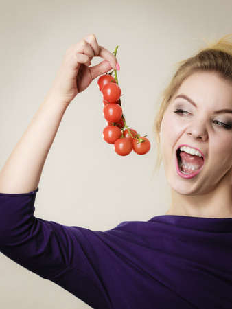 Organic vegetables and food concept. Happy positive smiling woman holding fresh cherry tomatoesの写真素材
