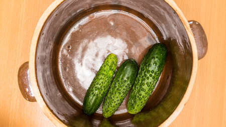Preparing sour low salt cucumbers in clay jar pot. View from aboveの写真素材