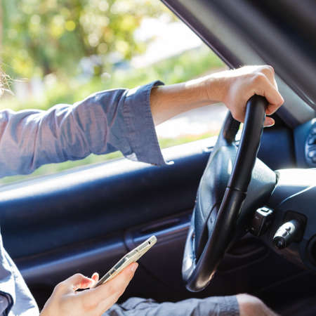 Modern technology concept. Man using mobile phone while driving car, checking social media or...