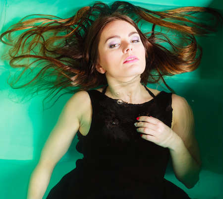 Sensuality and sexuality of women. Sexual posing woman in black dress in water. Indoor.の写真素材