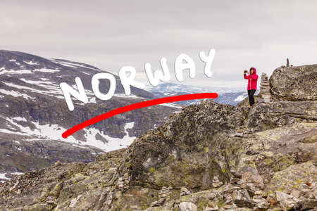 Tourism vacation and travel. Female tourist taking photo with camera, enjoying mountains landscape from Dalsnibba viewpoint, Norway Scandinavia.の写真素材