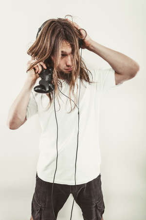 Addiction effects concept. Young unhappy depressed man with pad joystick playing games. Male addicted to console  videogames.の写真素材