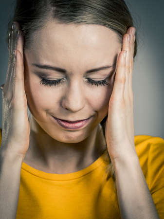 Young blonde woman having serious migrene suffering from horrible head ache feeling big pain.の写真素材
