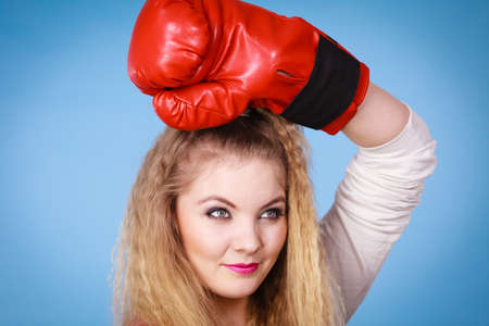 Cute blonde girl female boxer with big fun red gloves playing sports boxing studio shot on blueの写真素材