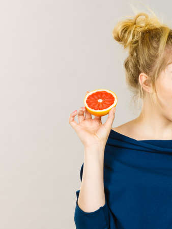 Healthy diet, refreshing food full of vitamins. Happy woman holding sweet delicious citrus fruit, red grapefruit.の写真素材