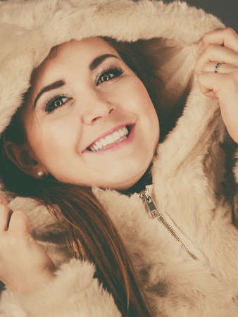 Happy attractive woman wearing light furry warm cozy coat with hood perfect for winter. Cold days fashion concept.の写真素材