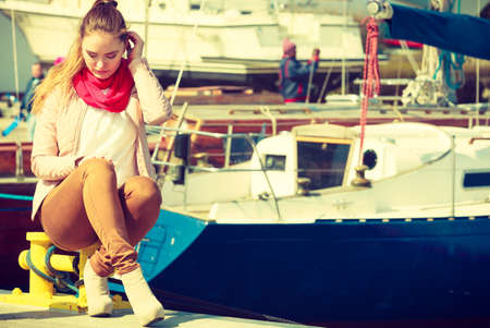 Woman sitting on bitt in marina waiting for somebody. Spring sunny weather, outdoor shot.の写真素材