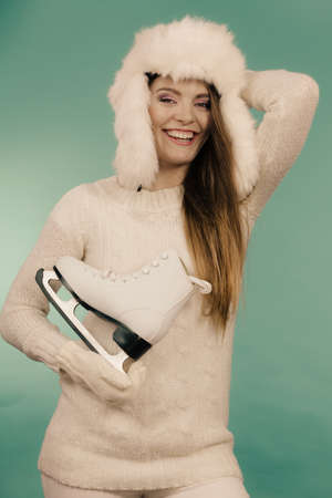 Woman carrying a pair of ice skates getting ready for ice skating, winter sport activity, on blueの写真素材