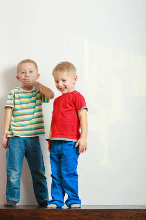 Childhood, relationship between brothers concept. Two little boys siblings playing together on table having fun.の写真素材