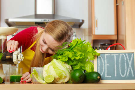 Drinks good for health, diet breakfast concept. Young woman in kitchen making green healthy vegetable smoothie juice from green vegetablesの写真素材