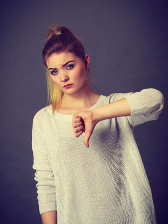 Sad unhappy woman showing thumb down gesture. Negative human face expressions and gestures concept.
