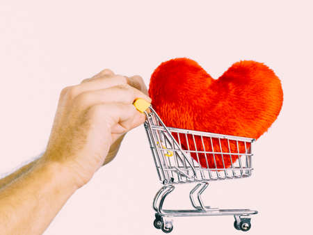 Male hands holding shopping basket cart with red heart. Love, valentines day, charity sharing concept.の写真素材